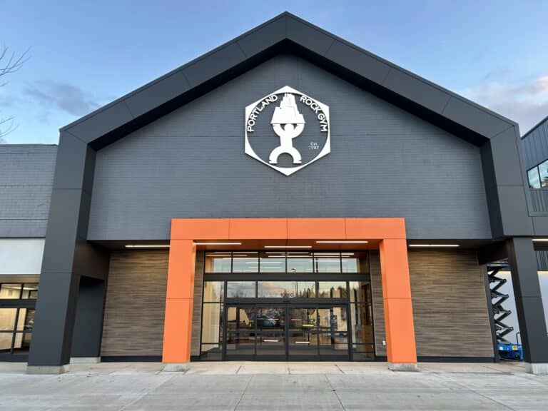 Modern commercial building with a black and orange facade and a unique white logo above the entrance.