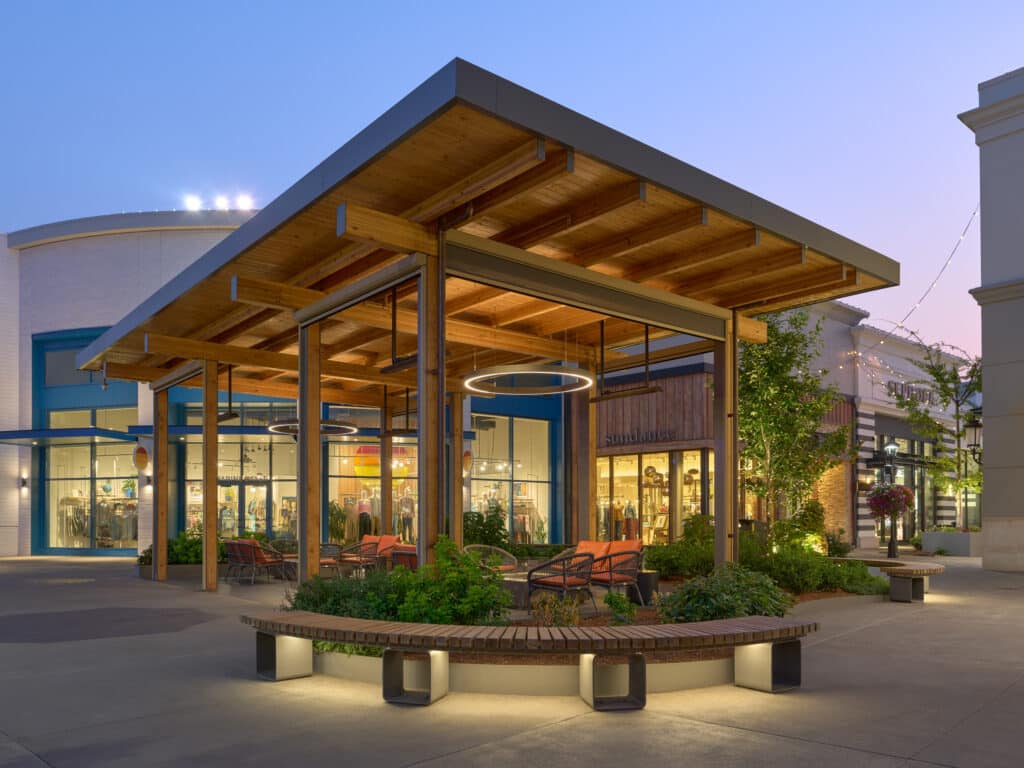 Modern covered seating area with warm lighting in a renovated community plaza.